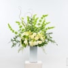 Tall white and green floral arrangement in a clear vase