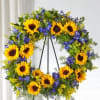 Sunflower wreath with blue flowers on a black stand
