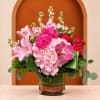 Pink and red floral arrangement in a glass vase with lilies and orchids