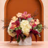 Bouquet of cream roses, hydrangeas, and pink orchids in a white vase