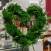 Heart-shaped green wreath on a stand with white wrapping