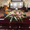 Pink and white floral casket spray on a dark wood casket