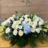 Low floral arrangement of white roses, lilies, and blue hydrangea