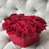 Red roses arranged in a pink heart-shaped box