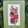 Framed embroidery of red roses on a green mat board