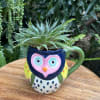 Succulent in a colorful owl-shaped mug on a wooden surface