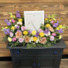 Colorful floral arrangement around a white picture frame on a black cabinet