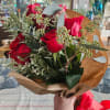 One dozen red roses wrapped in craft paper.