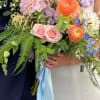 Bride and groom holding pastel wedding bouquets with roses and ranunculus