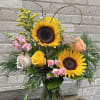 Sunflower and rose bouquet in a glass vase with curly branches