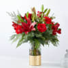 Red roses and lilies in a clear glass vase with gold wrap