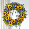 Sunflower wreath with blue and yellow flowers on a black stand