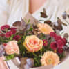 Bouquet of peach roses, pink carnations, and peach daisies