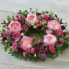 Pink and magenta floral wreath with large roses on a wood surface