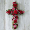 Cross-shaped floral arrangement with red roses and pink blooms