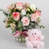 Pink and white bouquet in a glass vase with a pink teddy bear