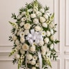 White floral wreath with roses, daisies, and a white ribbon bow