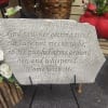 Memorial stone with engraved quote beside red and white roses