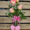 Pink roses in a glass vase with a heart topper and ribbon