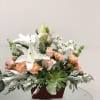 Arrangement of white lilies, peach roses, and carnations in a wooden container
