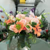 Peach roses and orange daisies in a clear glass vase