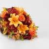 Autumn bouquet with orange lilies and roses in a woven horn-shaped container