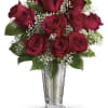 Red roses arranged in a clear glass vase with baby's breath