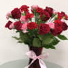 Red roses and pink carnations in a burgundy vase with a pink ribbon