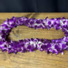 Purple and white orchid lei on a wooden table
