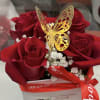 Red roses in a white box with a gold butterfly topper