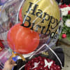 Birthday balloon bouquet with gold and red balloons over red roses
