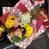 Mixed bouquet with roses, daisies, carnations, and baby's breath in red wrapping