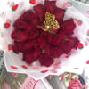 Bouquet of red roses wrapped in strawberry-patterned paper with a gold butterfly pick