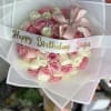Pink and white rose bouquet wrapped in translucent paper with a birthday ribbon
