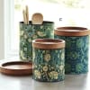 Three patterned canisters with wooden lids and utensils