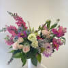 Mixed pink and lavender flowers arranged in a tall white vase