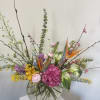 Mixed floral arrangement in a round glass vase with pink, yellow, purple, and orange blooms