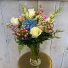 Mixed bouquet with white roses, blue hydrangea, and pink flowers in a glass vase