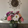 Mixed bouquet in a square glass vase with pink, white, and purple flowers