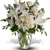 White lilies and roses arranged in a clear glass vase