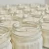 Rows of white candles in clear glass jars
