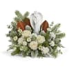 White roses arranged around an angel figurine with evergreen accents