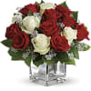 Red and white roses arranged in a clear square vase