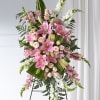 Tall standing spray with pink lilies, pale spray roses, and white snapdragons on a metal easel