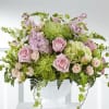Large pastel arrangement with pink roses, green mums, and hydrangeas in a white pedestal bowl