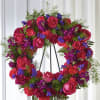 Bright pink and purple standing wreath of roses and carnations on a black metal easel