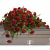 Long red carnation casket spray arranged atop a gray casket
