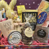 Gift basket with candy, a candle, a plush bunny, and a plaid ribbon