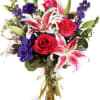 Bouquet of red roses, pink lilies, and purple flowers in a glass vase