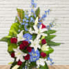 Standing floral spray with red roses, white lilies, and blue flowers